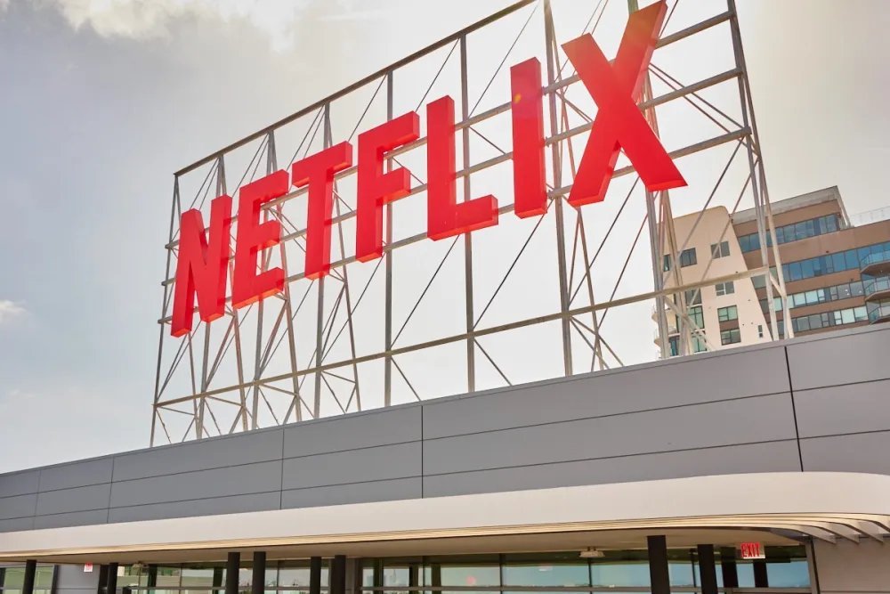 A large red Netflix sign mounted on a metal framework atop a corporate building.