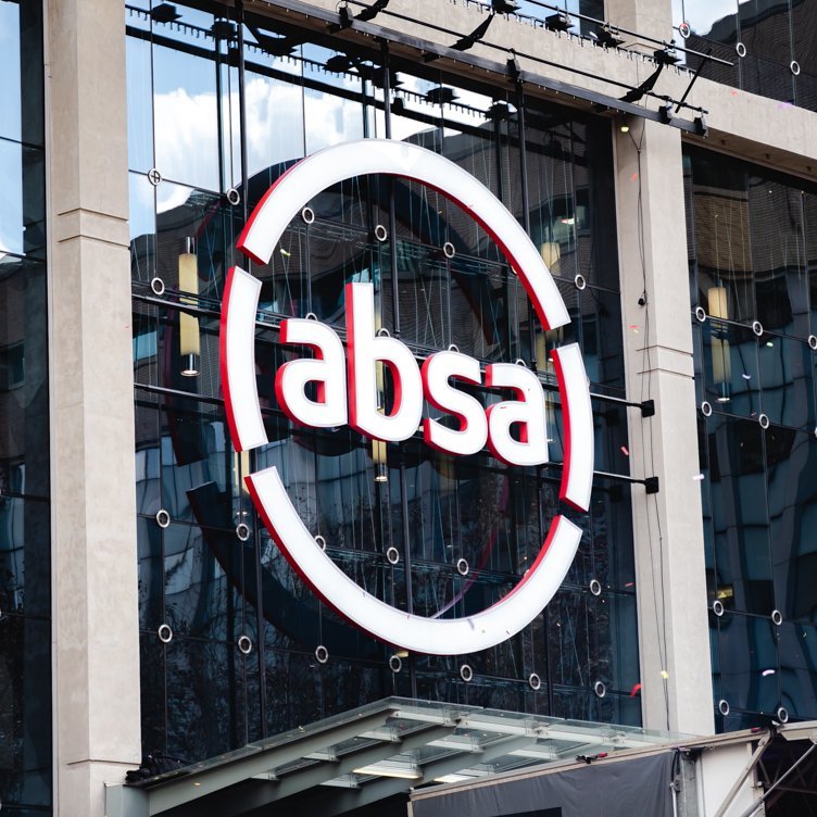 Absa circular red and white logo displayed on the glass facade of a building.