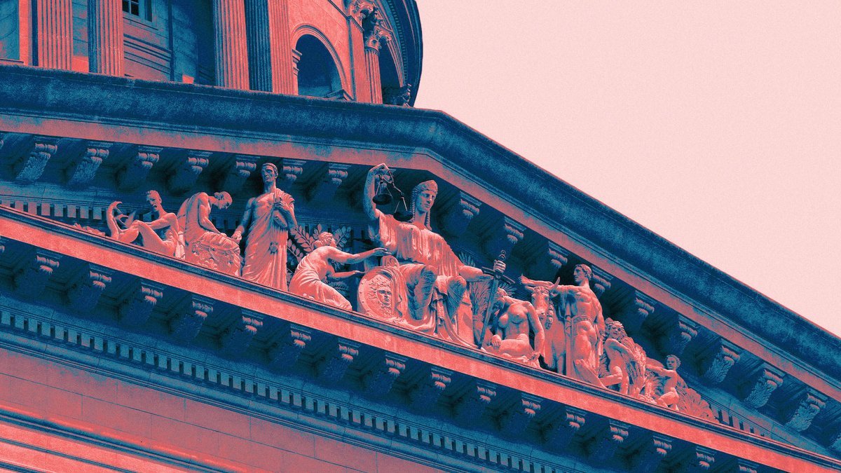 Carved sculptures including Lady Justice atop a classical courthouse pediment.