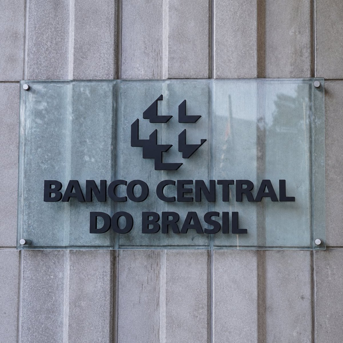 A glass sign on a concrete wall displaying the logo and name of Banco Central do Brasil.