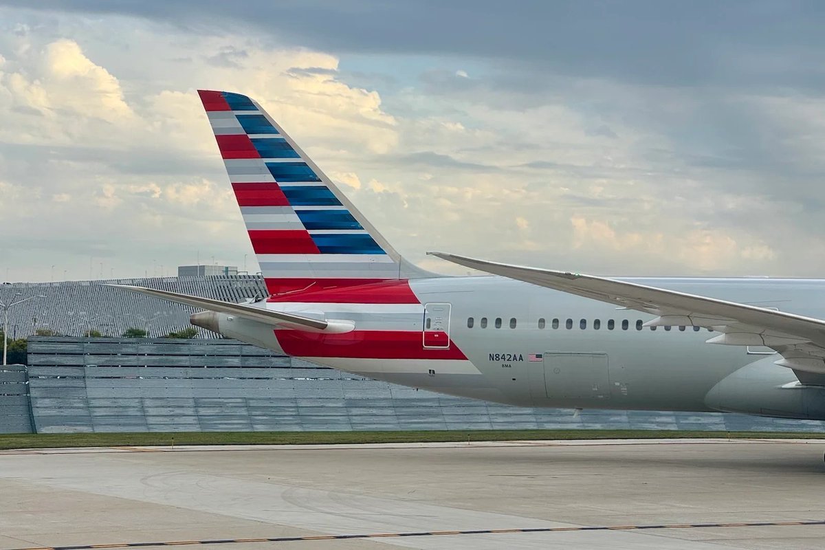 Tail and fuselage of an American Airlines commercial aircraft parked on an airport tarmac.