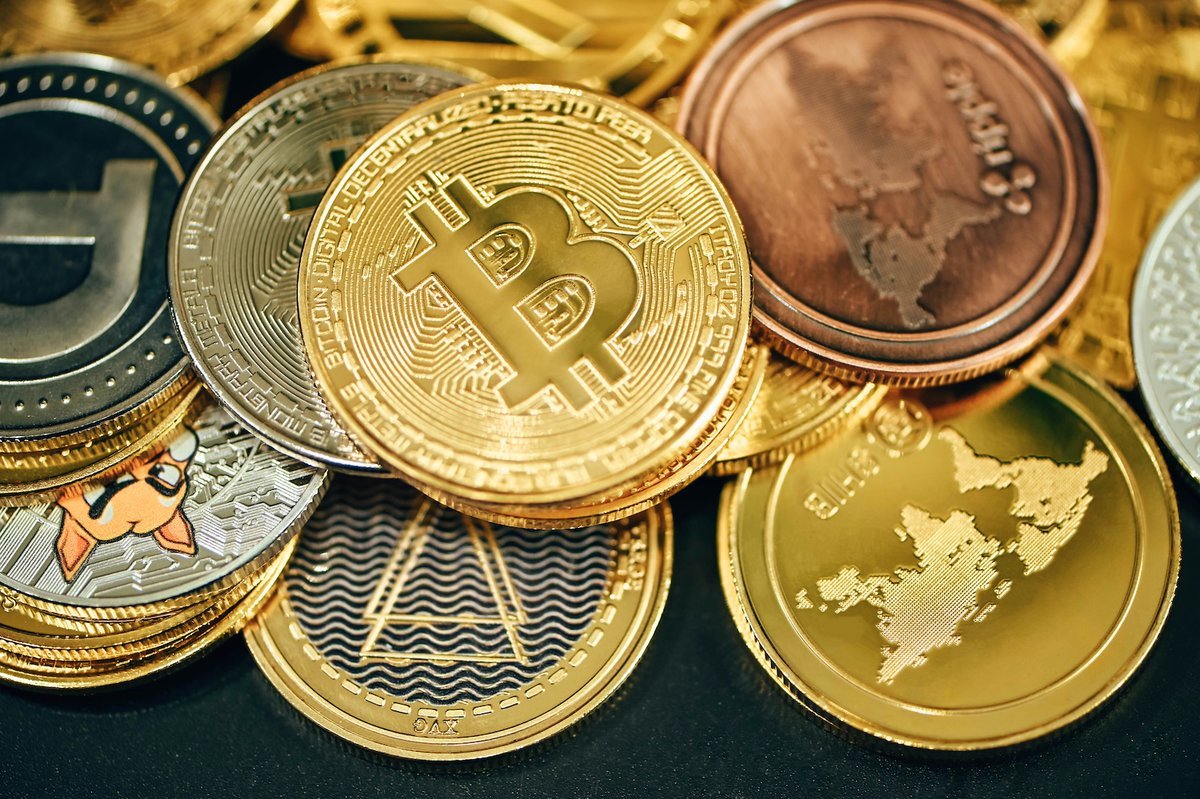 Physical commemorative tokens representing Bitcoin and other cryptocurrencies stacked together.