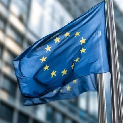 European Union flags waving on flagpoles in front of a modern glass office building.