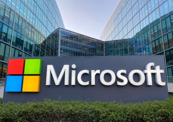 A large Microsoft corporate sign and logo positioned outside a modern glass-facade office building.