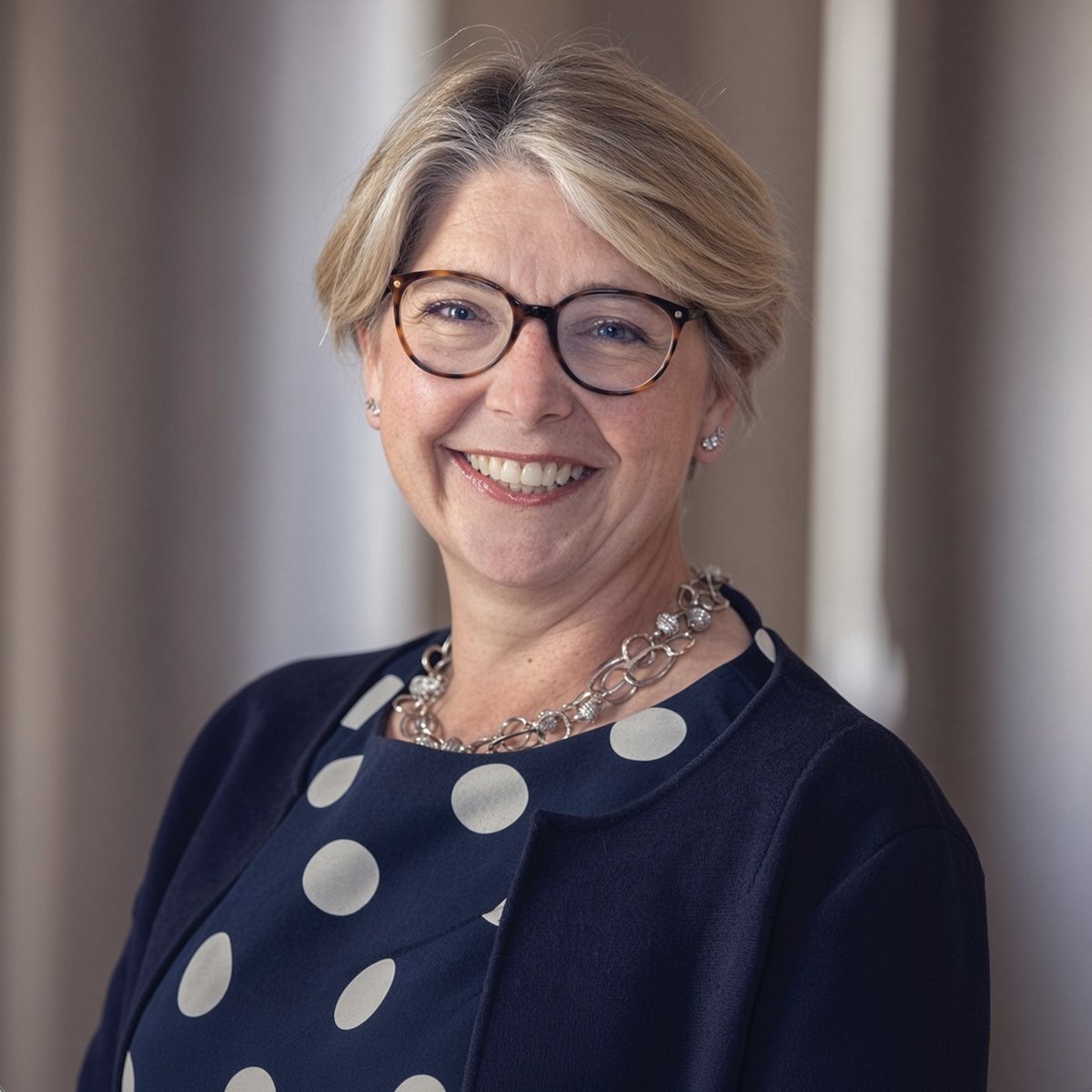 Portrait of Bank of England Deputy Governor Sarah Breeden smiling and wearing glasses.