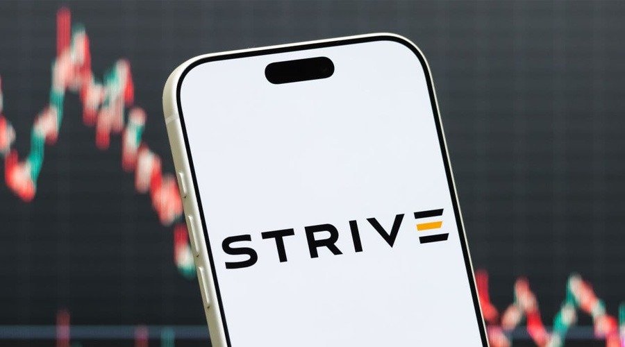 A smartphone displaying the Strive company logo against a blurred financial market candlestick chart background.