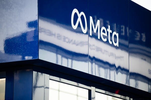 A close-up view of the Meta company logo and infinity symbol on a reflective blue building exterior.