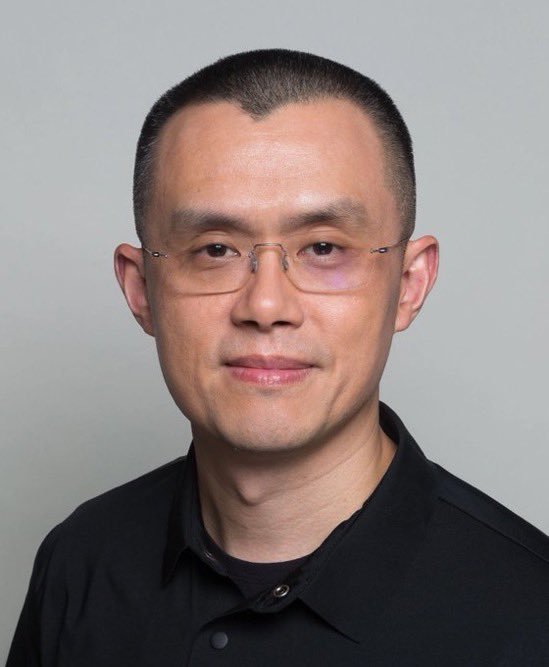 Portrait of Binance founder Changpeng Zhao wearing rimless glasses and a dark shirt against a neutral background.