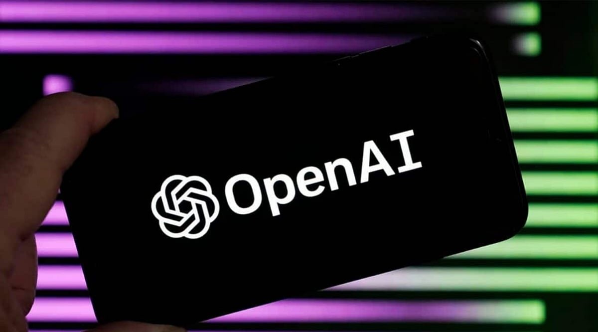 A smartphone screen displaying the OpenAI logo held in hand against a purple and green light background.
