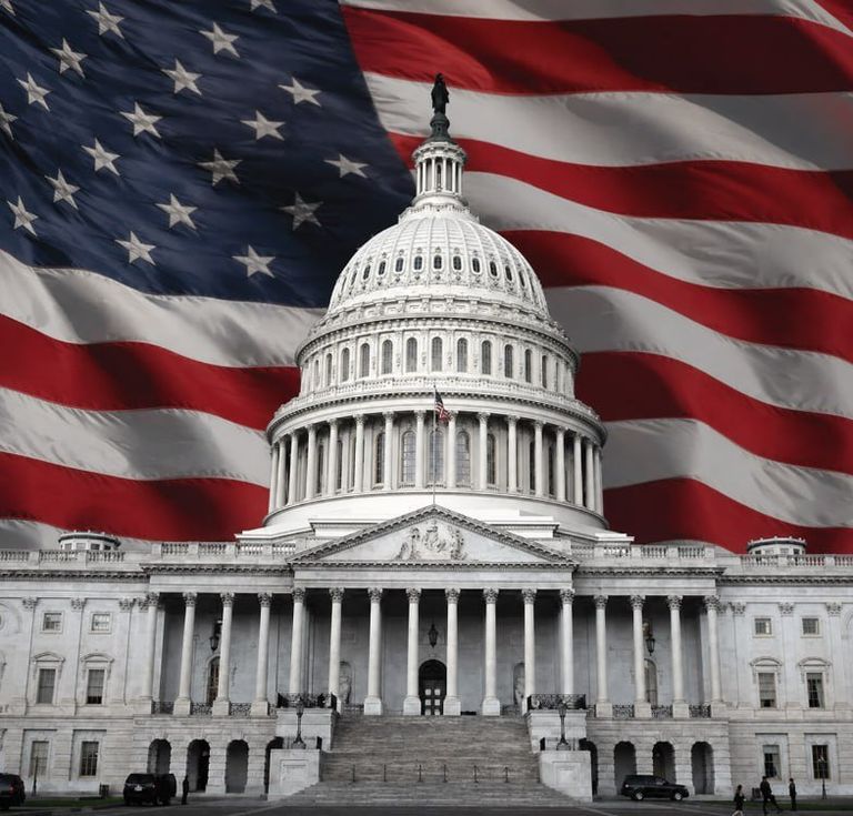 The United States Capitol building set against a waving American flag.