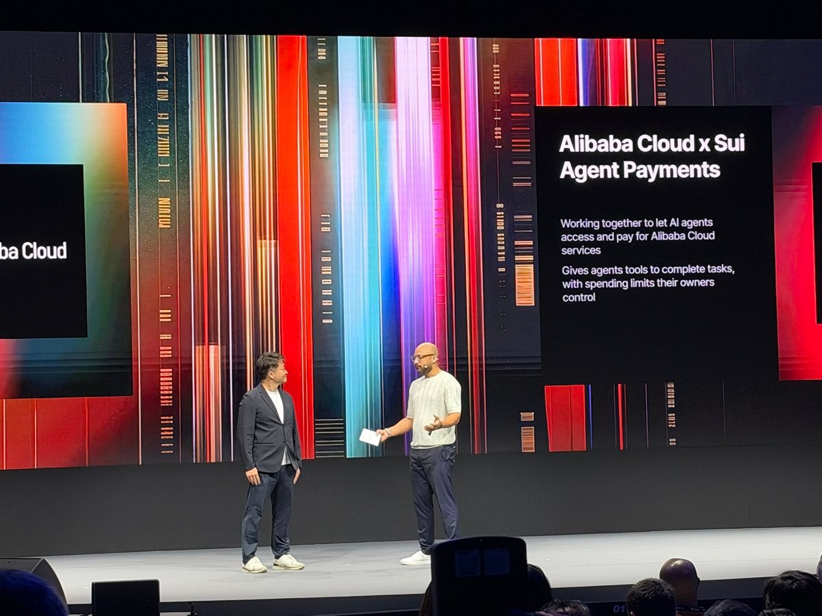 Two speakers on a conference stage in front of a presentation slide titled 'Alibaba Cloud x Sui Agent Payments'.
