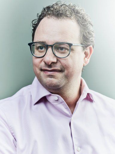 Portrait of Anthropic co-founder Dario Amodei wearing glasses and a light-colored collared shirt.