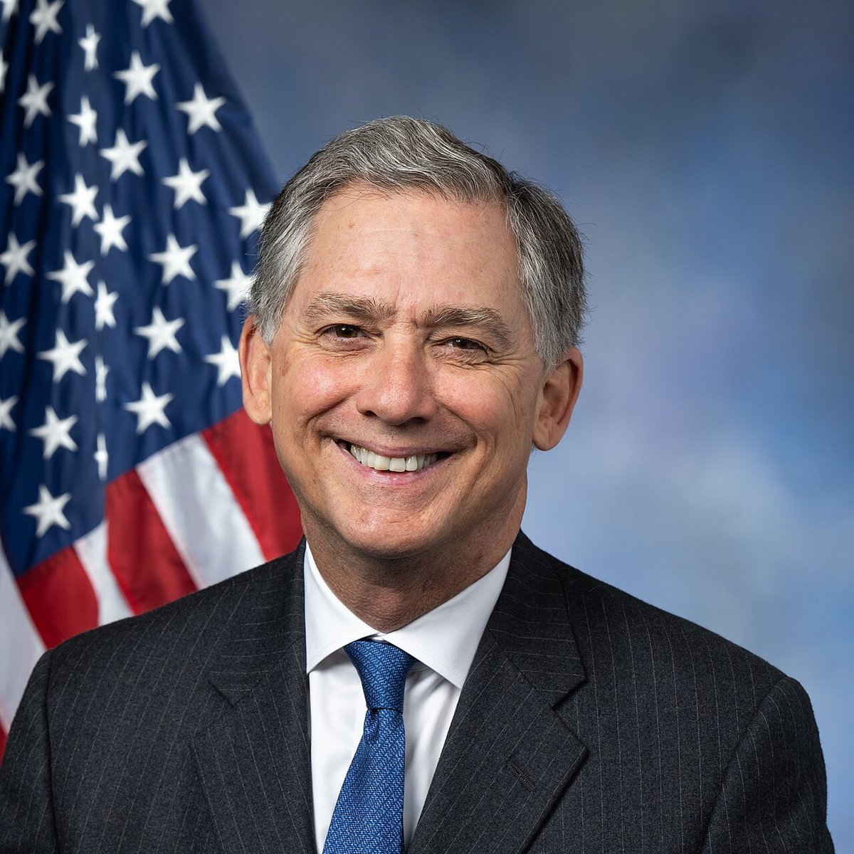 Official portrait of U.S. Representative French Hill smiling in front of the American flag.