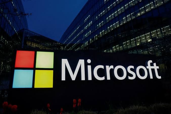 Illuminated Microsoft logo sign outside an office building at dusk