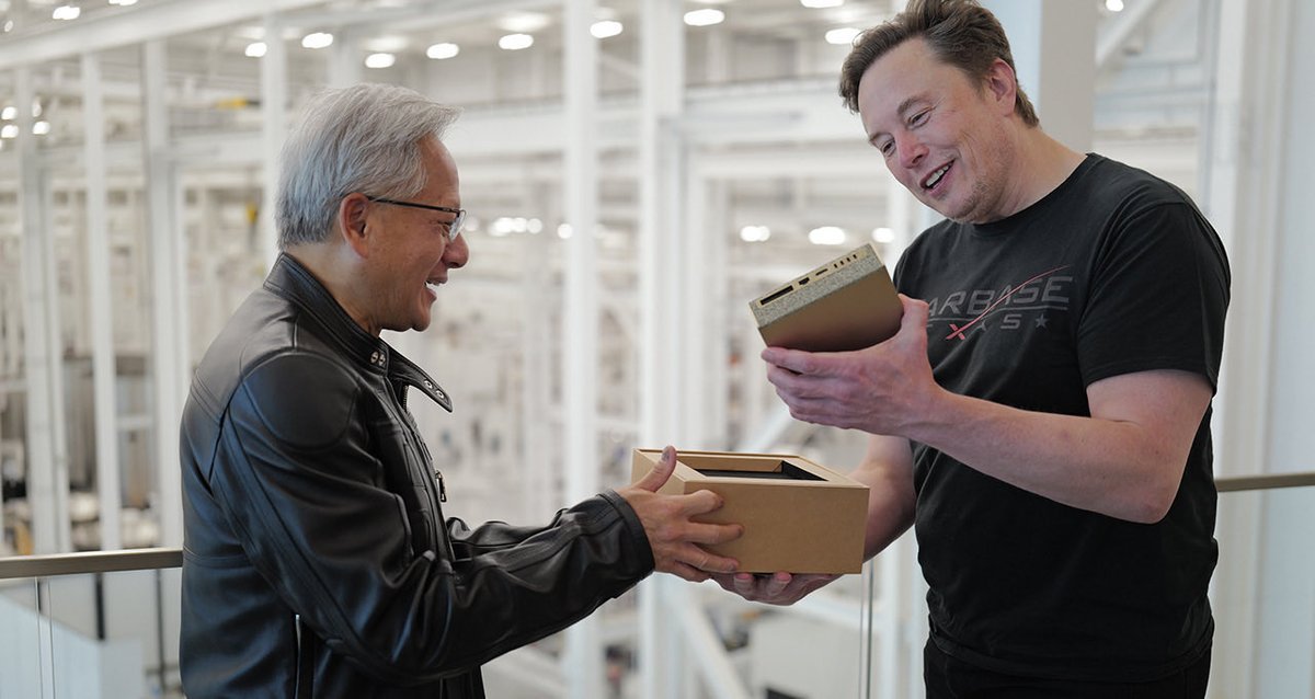 Nvidia CEO Jensen Huang handing a computing hardware unit to Elon Musk at a facility.