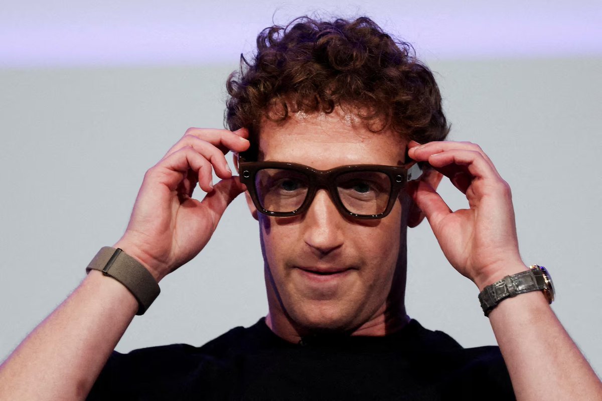 Mark Zuckerberg adjusting a pair of glasses.