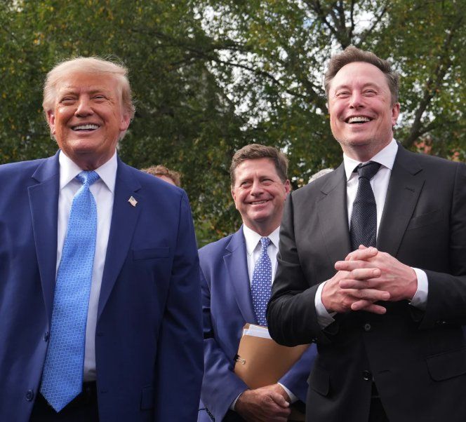 Donald Trump and Elon Musk standing outdoors together smiling in suits.