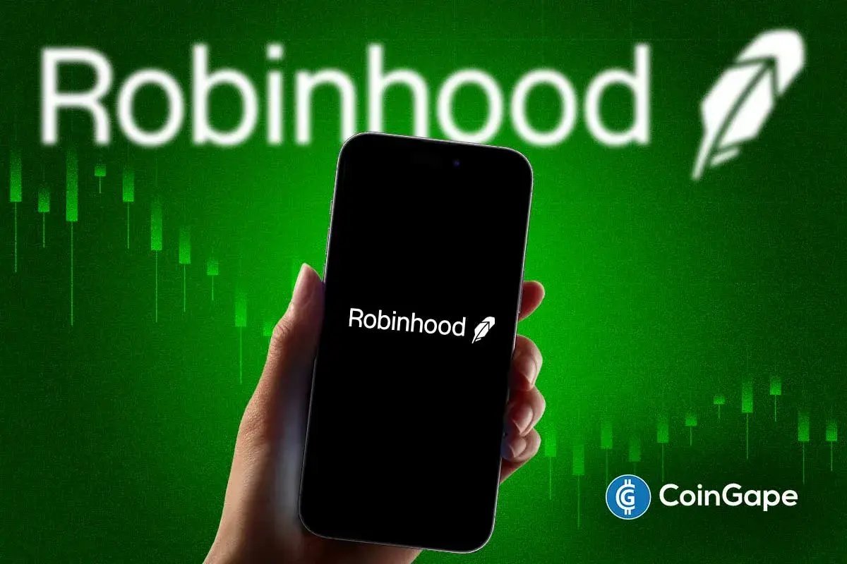 A hand holding a smartphone displaying the Robinhood logo against a green financial chart background.