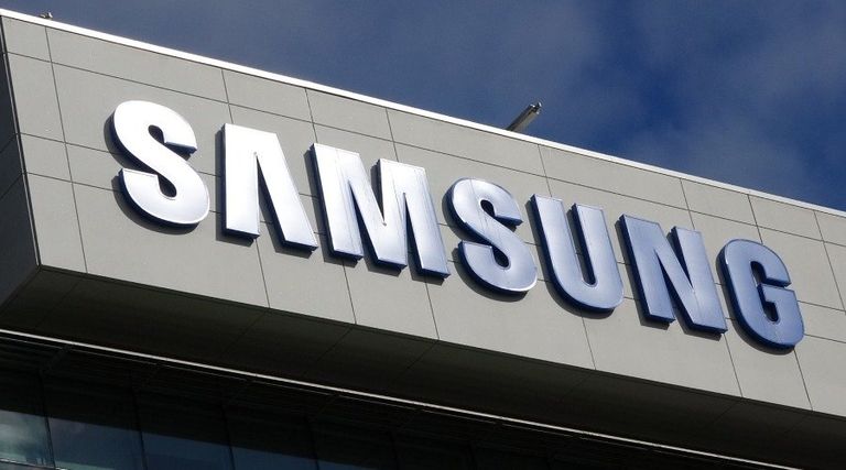 Samsung corporate logo mounted on the exterior of a building under a blue sky.