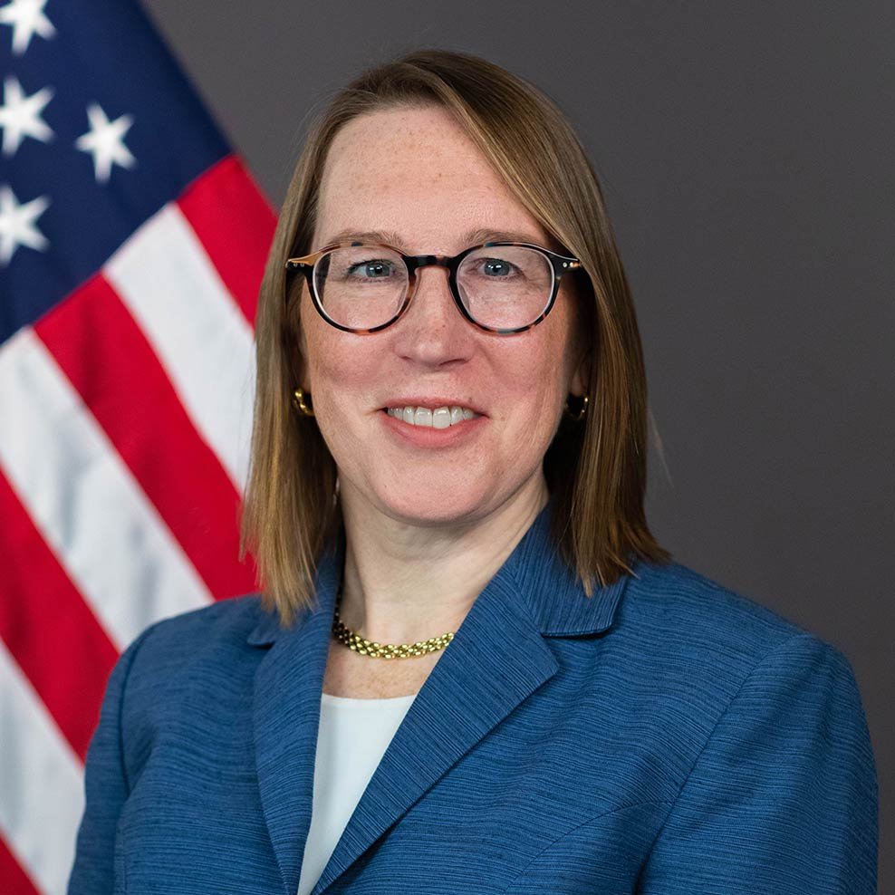 Official portrait of SEC Commissioner Hester Peirce against an American flag background.