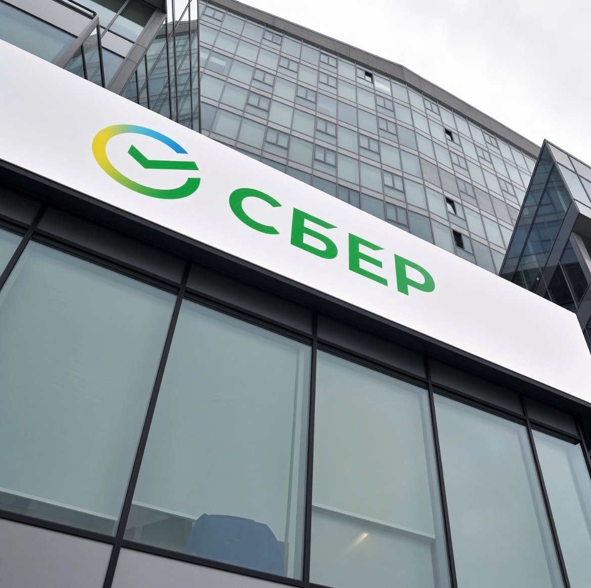 Exterior view of a modern glass office building with the Sberbank logo and name displayed on the facade.