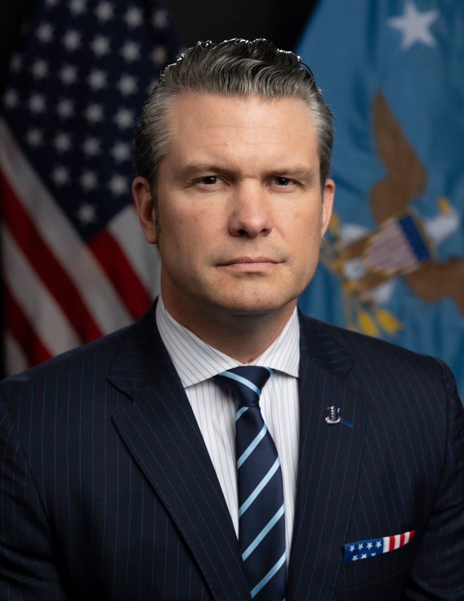 Official portrait of U.S. Defense Secretary Pete Hegseth in front of flags.