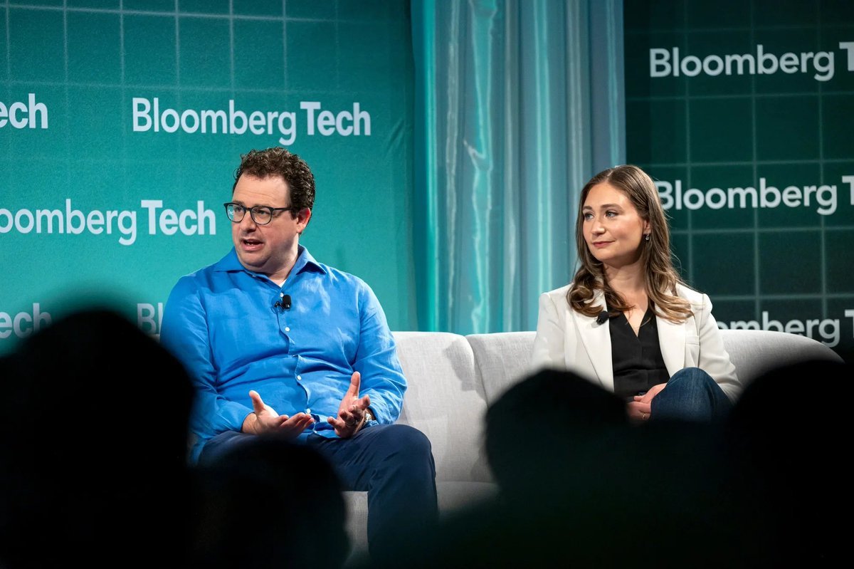 Anthropic co-founders Dario Amodei and Daniela Amodei speaking on a stage at a Bloomberg Tech event.