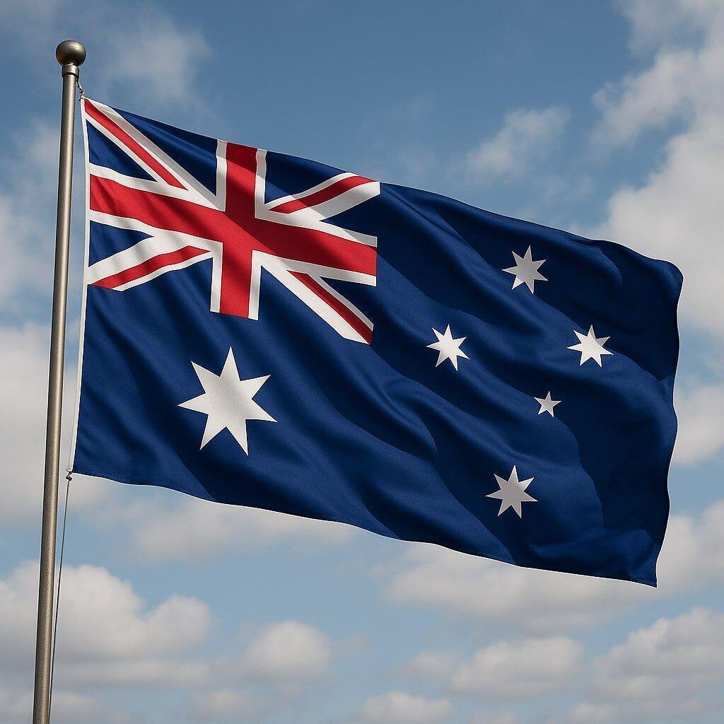 The national flag of Australia waving against a blue sky with clouds.