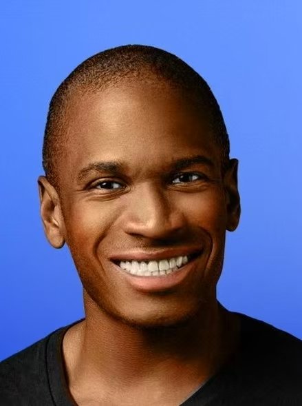 Portrait photograph of Arthur Hayes smiling against a solid blue background.