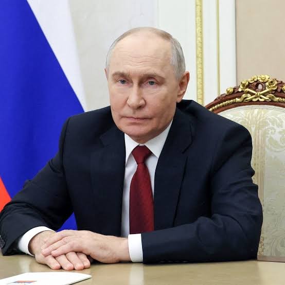 Russian President Vladimir Putin seated in a suit at a table.