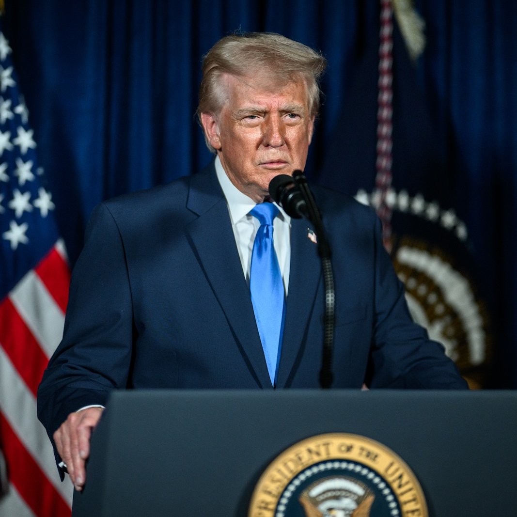 Donald Trump speaking at a podium with the Seal of the President of the United States.