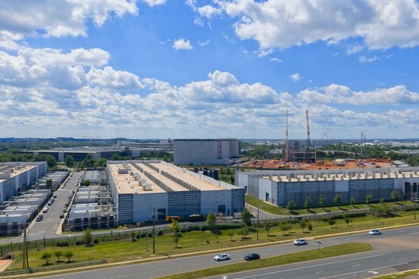 Aerial view of large data center facilities and warehouse buildings under a partly cloudy sky