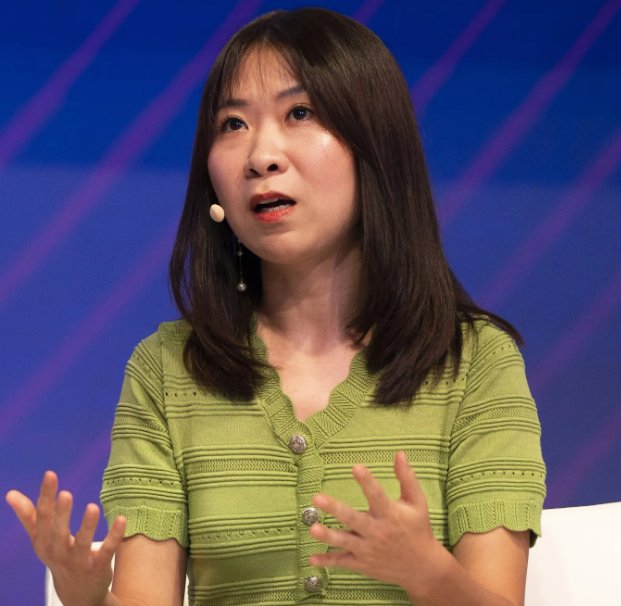 Constance Wang speaking on stage while gesturing with her hands.