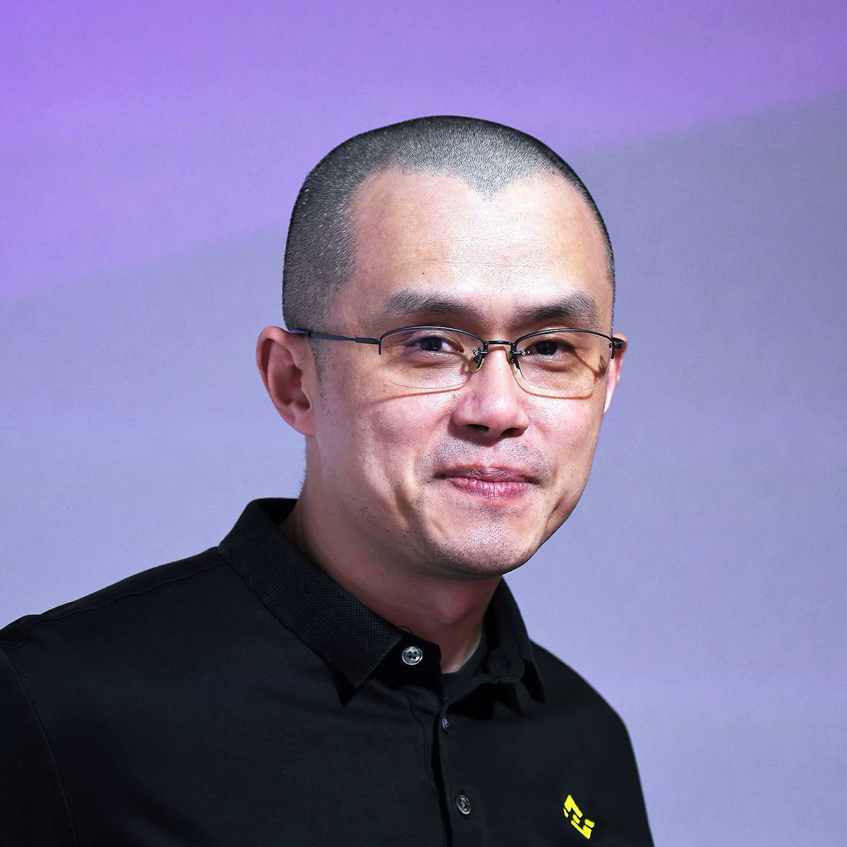 Portrait of Changpeng Zhao (CZ) wearing glasses and a black collared shirt.
