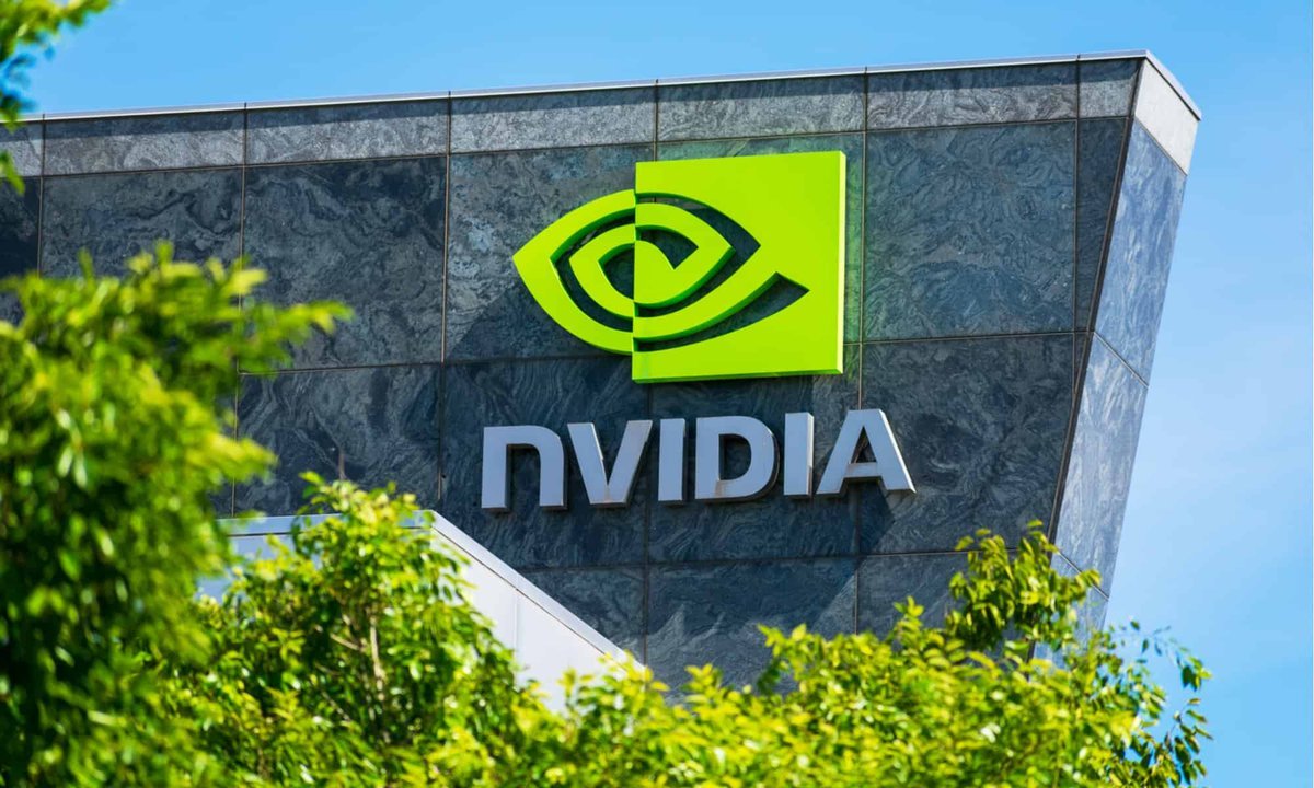 Nvidia logo and sign on an exterior building wall behind green leaves.