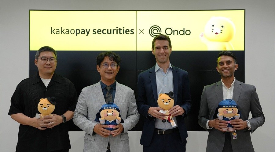Representatives from Kakao Pay Securities and Ondo Finance stand together holding plush mascots in front of a digital screen displaying 'kakaopay securities x Ondo'.