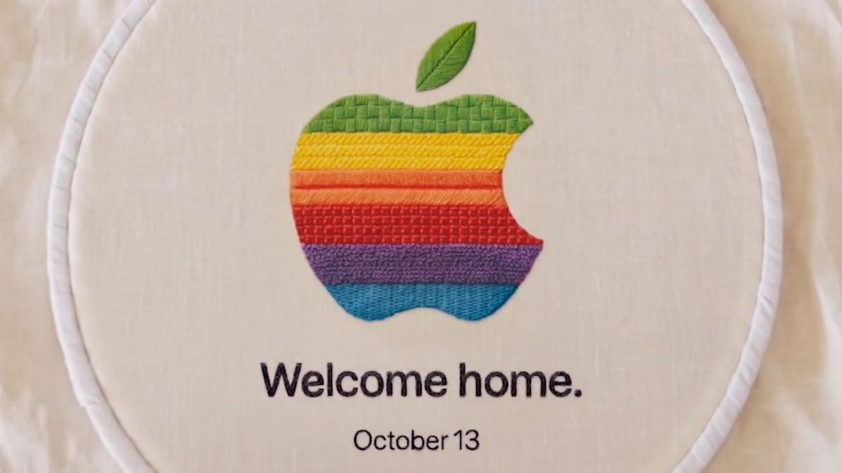 An embroidered rainbow Apple logo inside an embroidery hoop, with text reading 'Welcome home.' and 'October 13'.