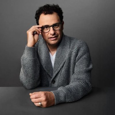 Portrait of Anthropic CEO Dario Amodei resting his head on his hand against a gray background.