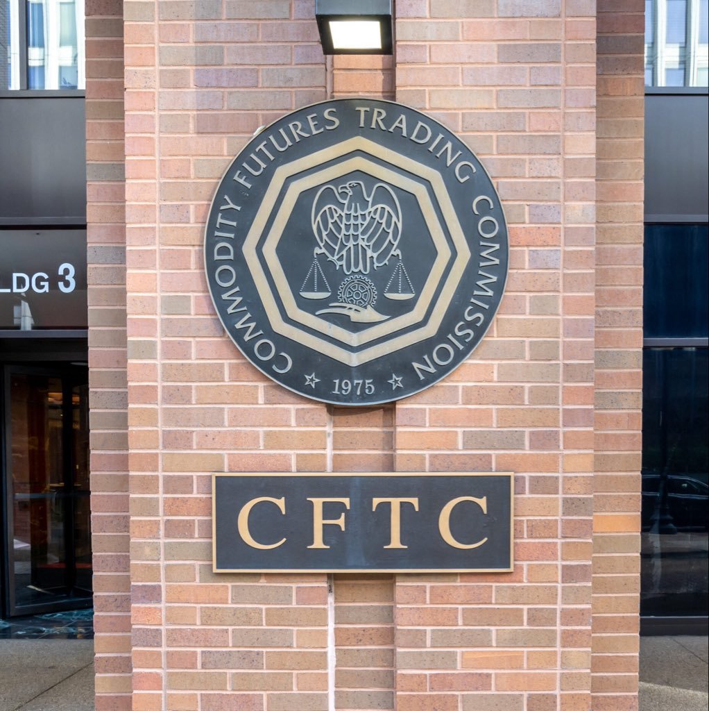 A bronze seal and sign for the Commodity Futures Trading Commission mounted on an exterior brick wall.
