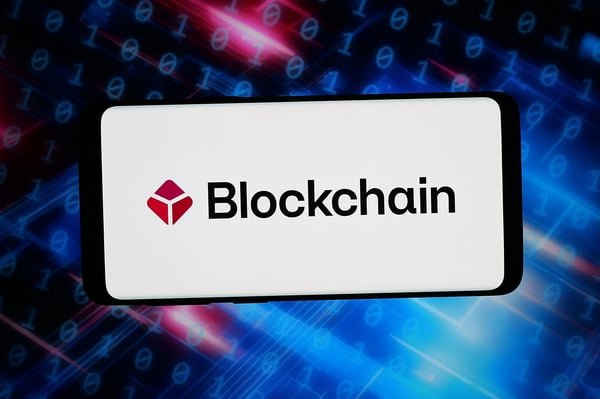 A smartphone screen displaying the Blockchain.com logo against a digital background.