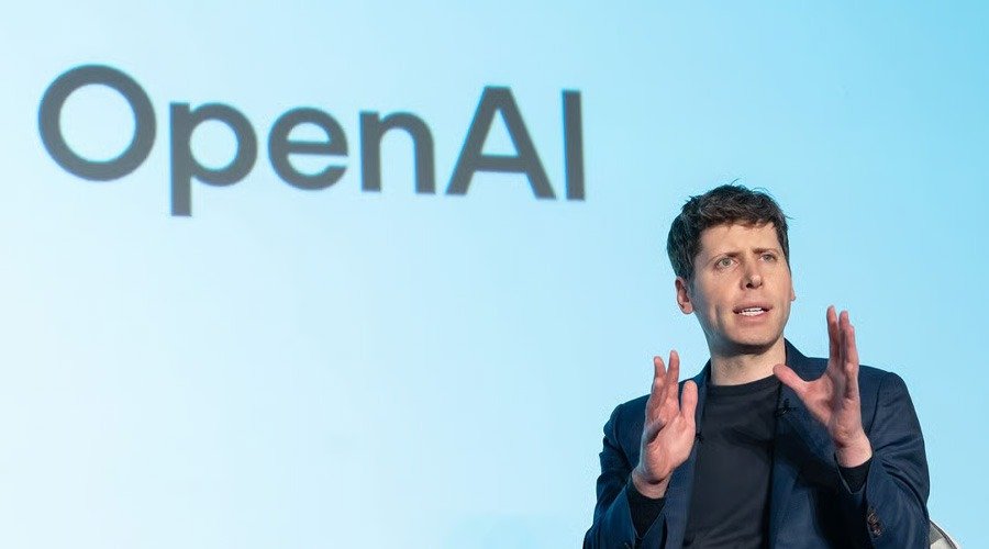 OpenAI CEO Sam Altman gesturing while speaking on stage in front of an OpenAI logo.
