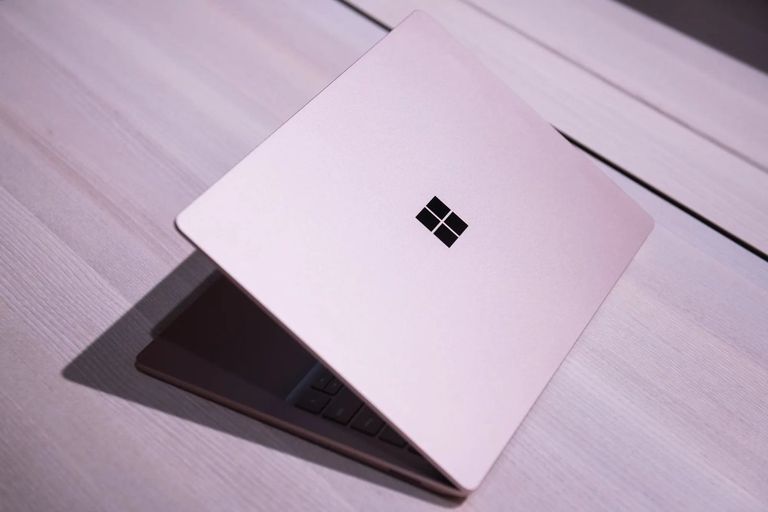 A partially open Microsoft Surface laptop viewed from above resting on a wooden surface.