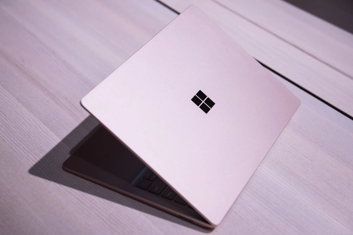 A partially open Microsoft Surface laptop viewed from above resting on a wooden surface.
