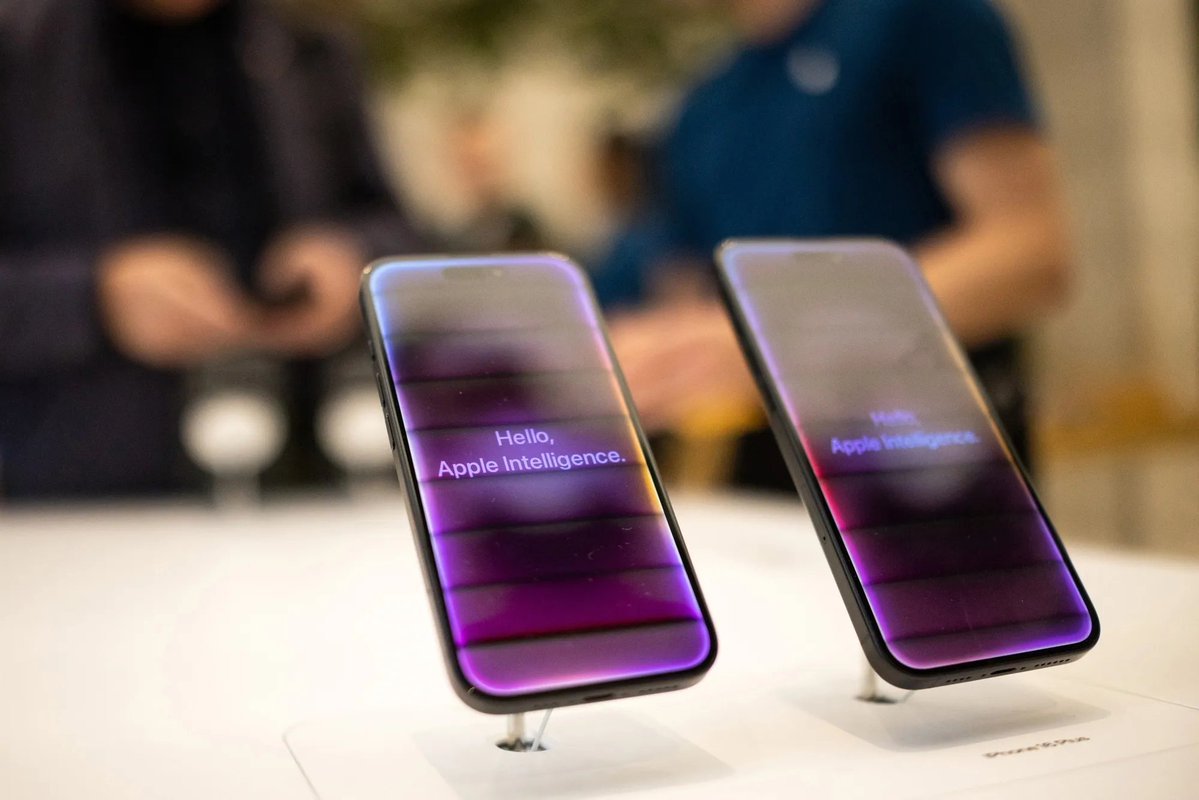 Smartphones on display stands showing screens that read 'Hello, Apple Intelligence.'