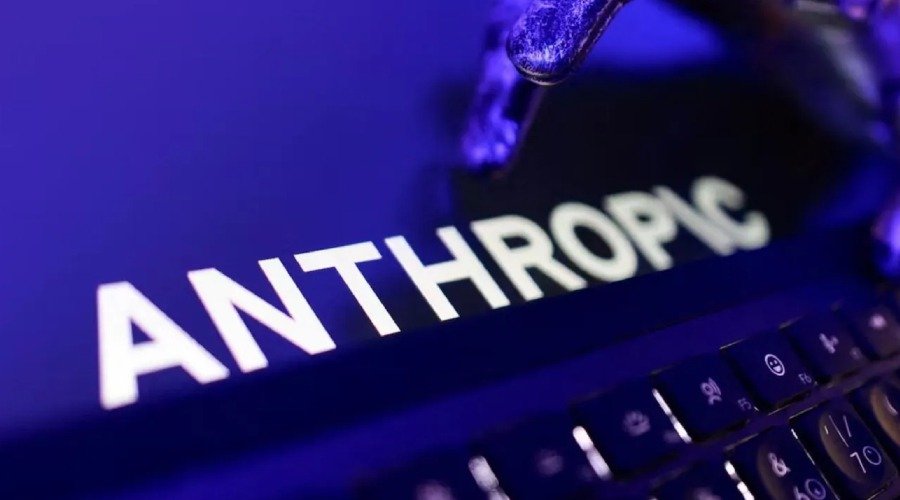 The Anthropic logo illuminated on a screen with a keyboard in the foreground under blue lighting.