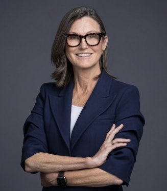 Portrait of Cathie Wood wearing glasses and a dark blue suit jacket