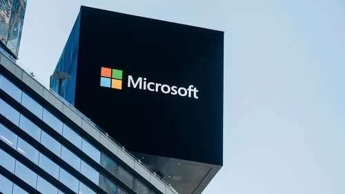 A large Microsoft logo displayed on an architectural structure atop a modern office building.